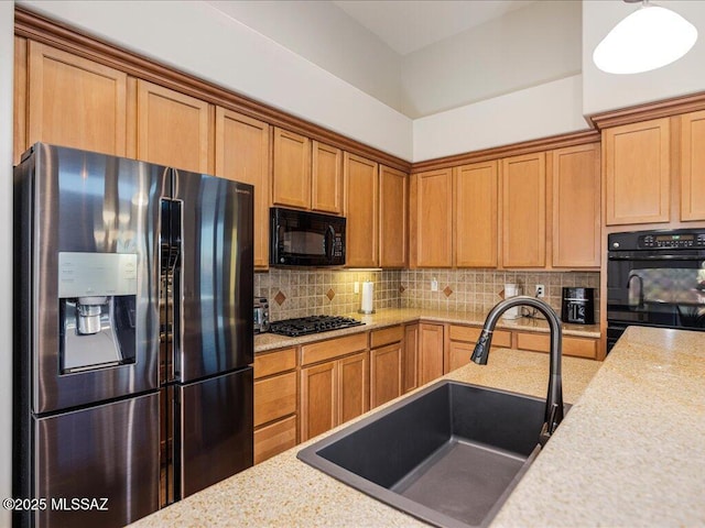 kitchen with decorative light fixtures, tasteful backsplash, sink, light stone counters, and black appliances