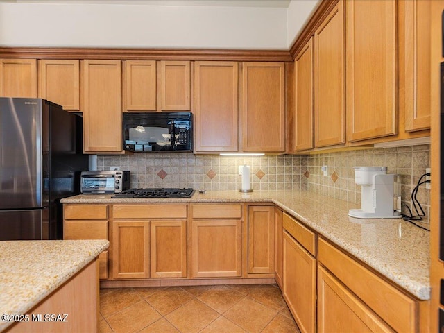 kitchen with tasteful backsplash, light stone countertops, light tile patterned floors, and black appliances