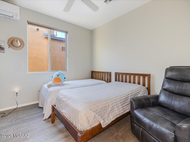 bedroom with hardwood / wood-style floors, a wall mounted AC, and ceiling fan