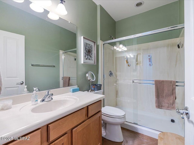 bathroom featuring a shower with door, vanity, tile patterned flooring, and toilet