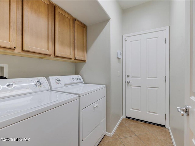 clothes washing area with cabinets, light tile patterned flooring, and washing machine and clothes dryer