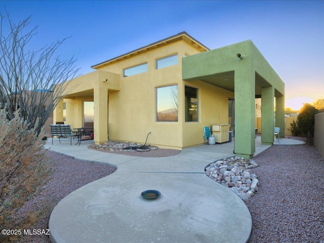 back house at dusk with a patio area