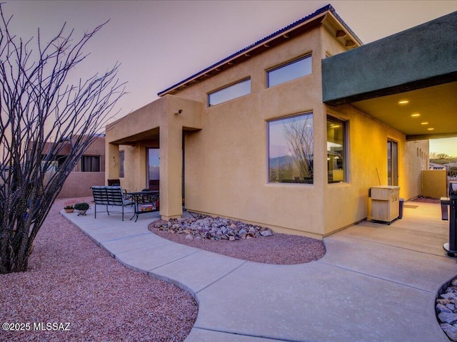 back house at dusk featuring a patio area