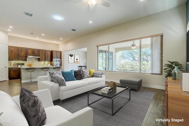 living room featuring ceiling fan and dark hardwood / wood-style floors