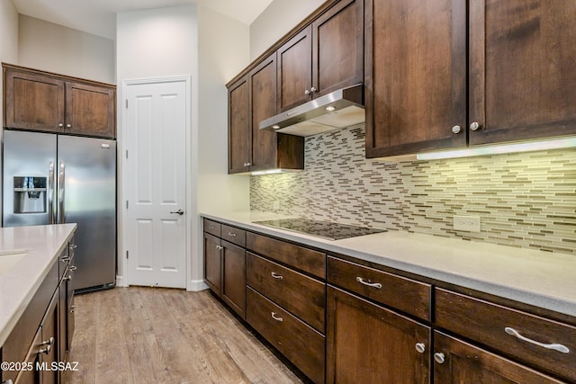 kitchen featuring black electric cooktop, backsplash, stainless steel fridge with ice dispenser, and dark brown cabinetry