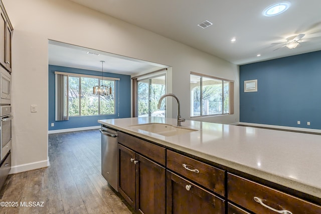 kitchen with dark brown cabinetry, wood-type flooring, stainless steel appliances, sink, and hanging light fixtures