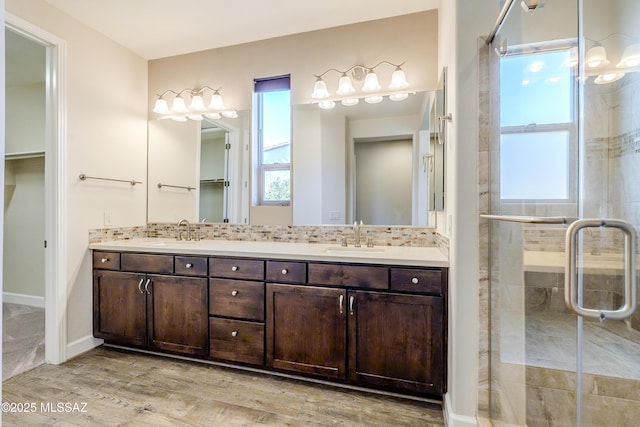 bathroom with vanity, a shower with door, hardwood / wood-style floors, and tasteful backsplash