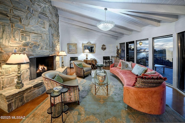 living room with a stone fireplace, a chandelier, and lofted ceiling with beams