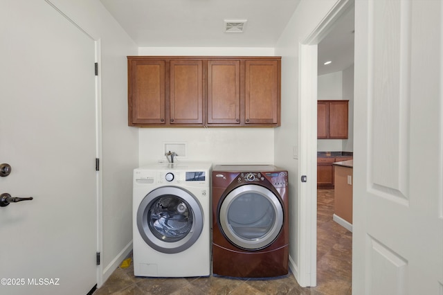 clothes washing area featuring washing machine and dryer and cabinets