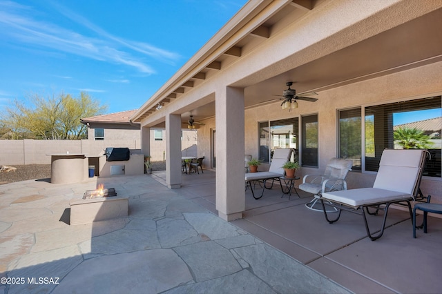 view of patio / terrace with ceiling fan, an outdoor fire pit, and exterior kitchen