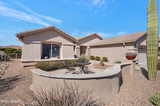 rear view of property with a garage and a patio