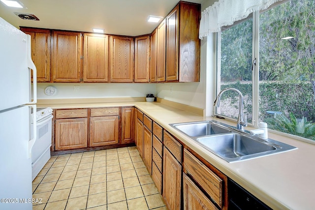 kitchen with a sink, light tile patterned floors, brown cabinets, and white appliances