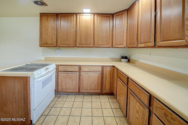 kitchen featuring brown cabinetry, visible vents, white range with electric cooktop, light countertops, and light tile patterned flooring