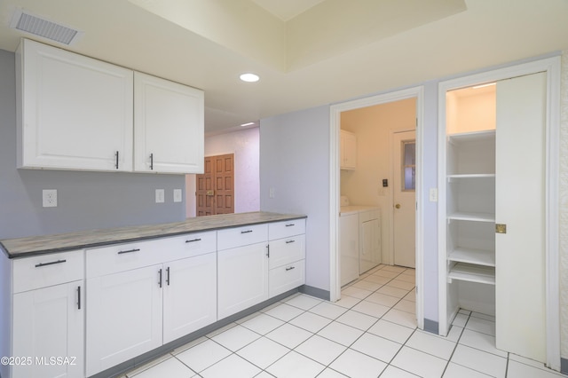 kitchen featuring white cabinetry, washing machine and clothes dryer, and light tile patterned flooring