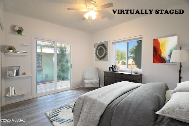 bedroom with hardwood / wood-style floors, access to outside, a textured ceiling, and multiple windows