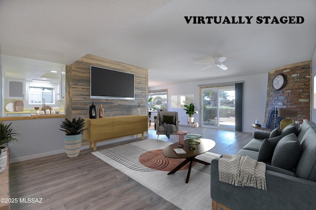 living room featuring a healthy amount of sunlight, hardwood / wood-style floors, a fireplace, and wood walls