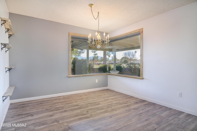 spare room featuring hardwood / wood-style floors, a textured ceiling, and a chandelier