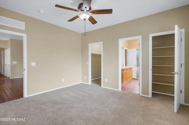 unfurnished bedroom featuring connected bathroom, a spacious closet, light carpet, and a closet