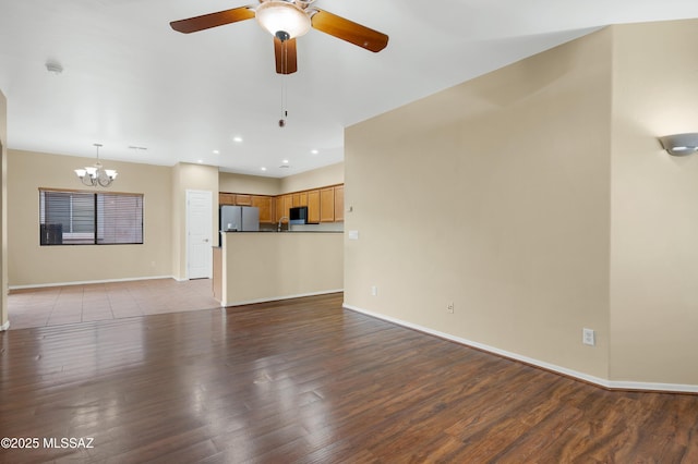 unfurnished living room with ceiling fan with notable chandelier and light hardwood / wood-style flooring
