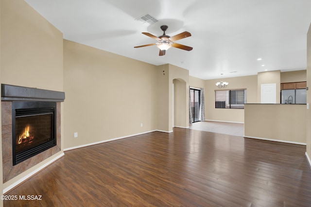 unfurnished living room featuring ceiling fan with notable chandelier, a fireplace, and light hardwood / wood-style flooring