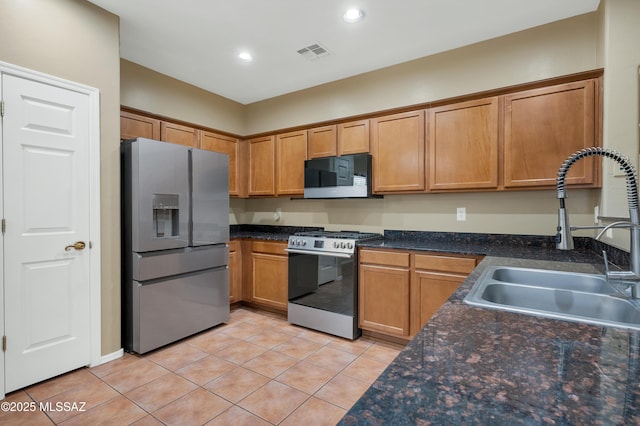 kitchen with appliances with stainless steel finishes, sink, and light tile patterned floors