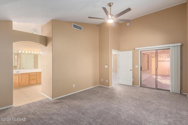 interior space with light carpet, ensuite bathroom, ceiling fan, high vaulted ceiling, and sink