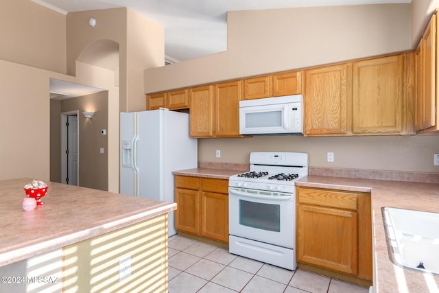 kitchen with sink, white appliances, light tile patterned floors, and a towering ceiling