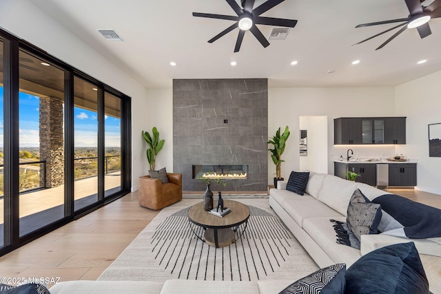 living room featuring ceiling fan, light hardwood / wood-style flooring, and a tile fireplace