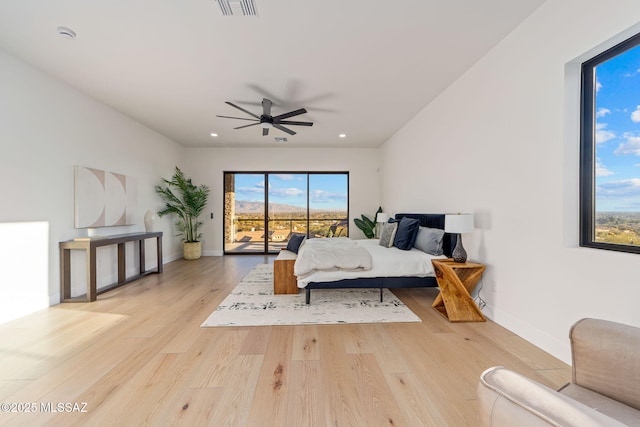 bedroom with ceiling fan, access to exterior, multiple windows, and light wood-type flooring