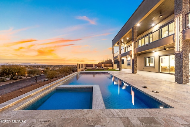 pool at dusk with a patio area, an in ground hot tub, and ceiling fan