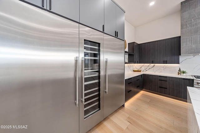 kitchen featuring stainless steel built in fridge, light wood-type flooring, and tasteful backsplash