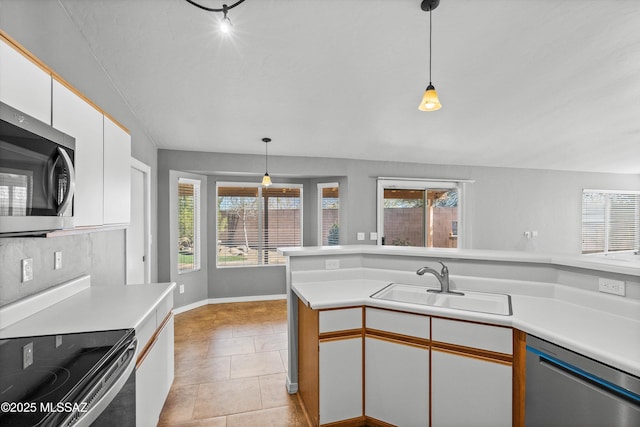 kitchen featuring stainless steel appliances, sink, white cabinets, and decorative light fixtures