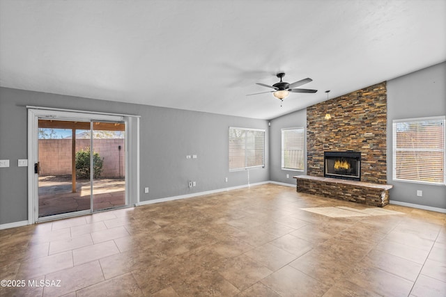 unfurnished living room featuring lofted ceiling, ceiling fan, a fireplace, and a healthy amount of sunlight