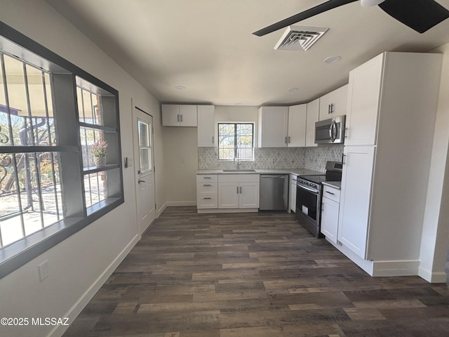 kitchen featuring appliances with stainless steel finishes, dark hardwood / wood-style floors, backsplash, white cabinets, and sink