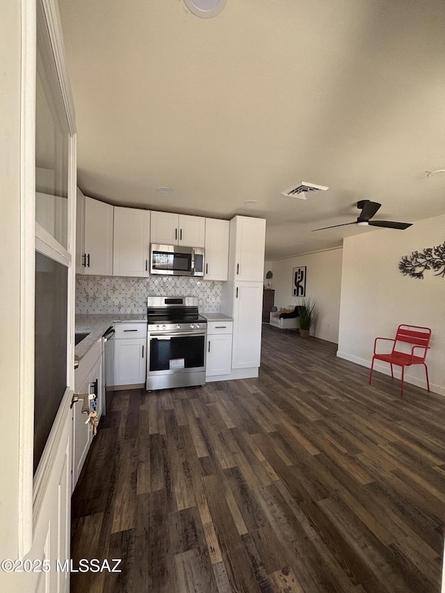 kitchen with white cabinetry, ceiling fan, appliances with stainless steel finishes, dark hardwood / wood-style floors, and backsplash