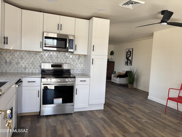 kitchen featuring stainless steel appliances, decorative backsplash, white cabinetry, and light stone countertops