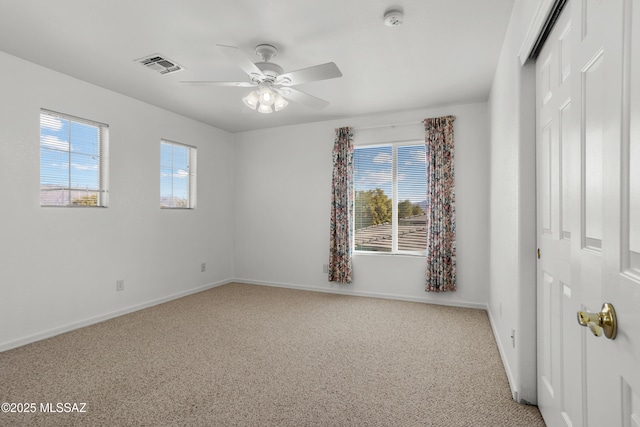 unfurnished room with ceiling fan, light colored carpet, and a wealth of natural light