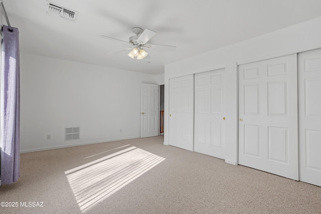 unfurnished bedroom featuring multiple closets and ceiling fan