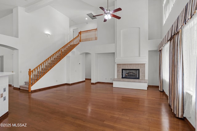 unfurnished living room with a tile fireplace, dark hardwood / wood-style floors, and a healthy amount of sunlight