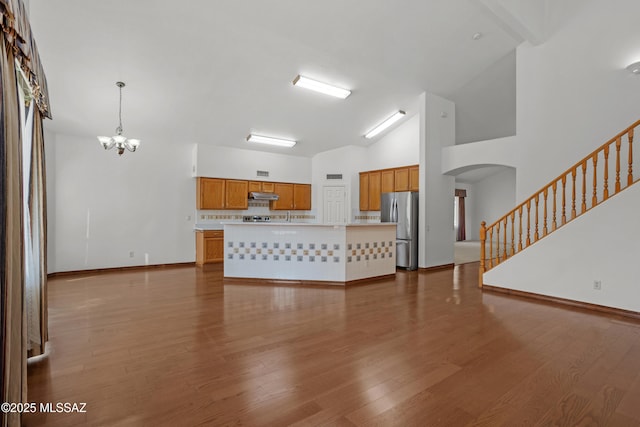 unfurnished living room with an inviting chandelier, a towering ceiling, and wood-type flooring