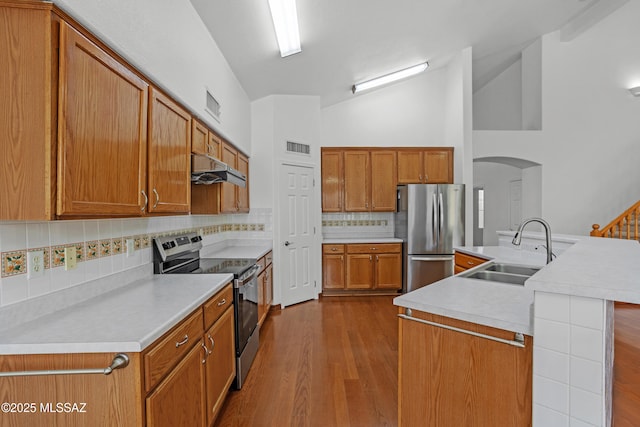 kitchen featuring sink, a center island with sink, hardwood / wood-style flooring, stainless steel appliances, and decorative backsplash