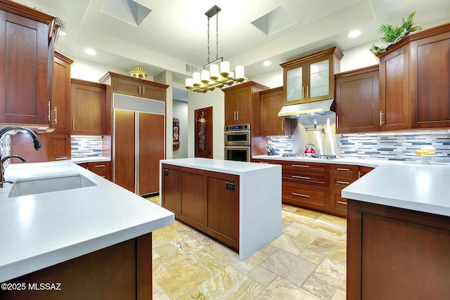 kitchen featuring decorative light fixtures, sink, decorative backsplash, a center island, and paneled fridge