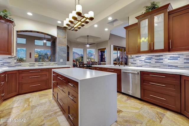 kitchen featuring pendant lighting, sink, dishwasher, a kitchen island, and a raised ceiling