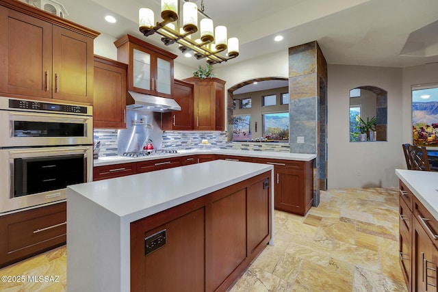 kitchen with stainless steel appliances, a kitchen island, pendant lighting, and decorative backsplash