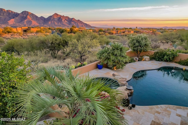 pool at dusk with a mountain view and a patio