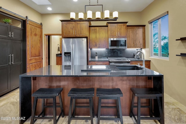 kitchen with a center island, sink, a barn door, and appliances with stainless steel finishes