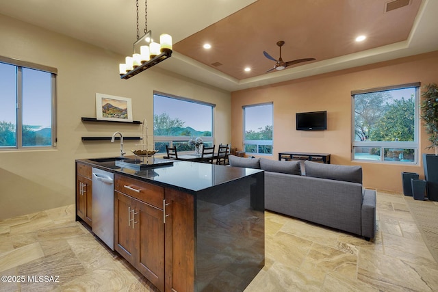 kitchen featuring sink, a raised ceiling, dishwasher, pendant lighting, and a kitchen island with sink