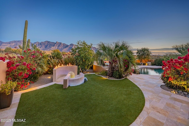 yard at dusk with a mountain view and a patio area