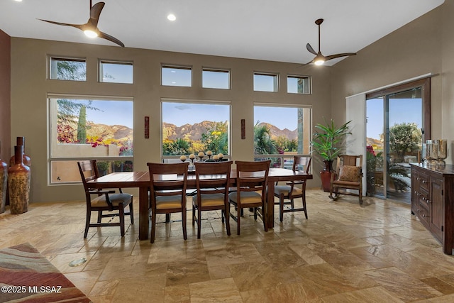 dining area featuring ceiling fan, a mountain view, and a high ceiling