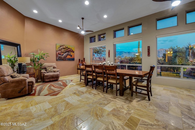 dining space featuring ceiling fan and a towering ceiling